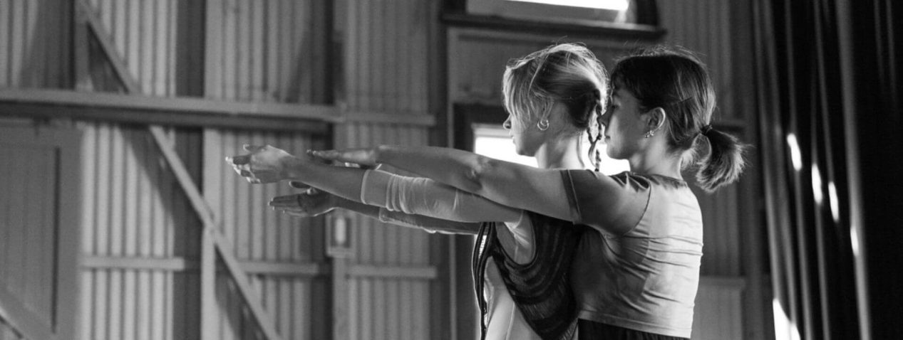 Two people standing close together with arms outstretched.