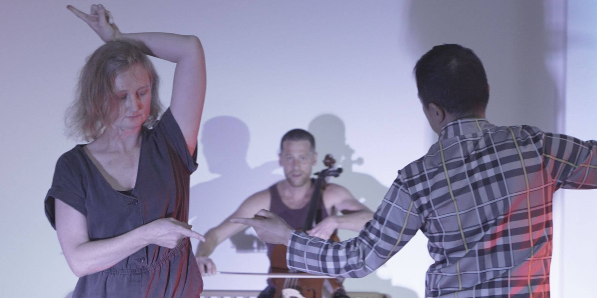 A person lying on their back on the floor of a performance space surrounded by ash.