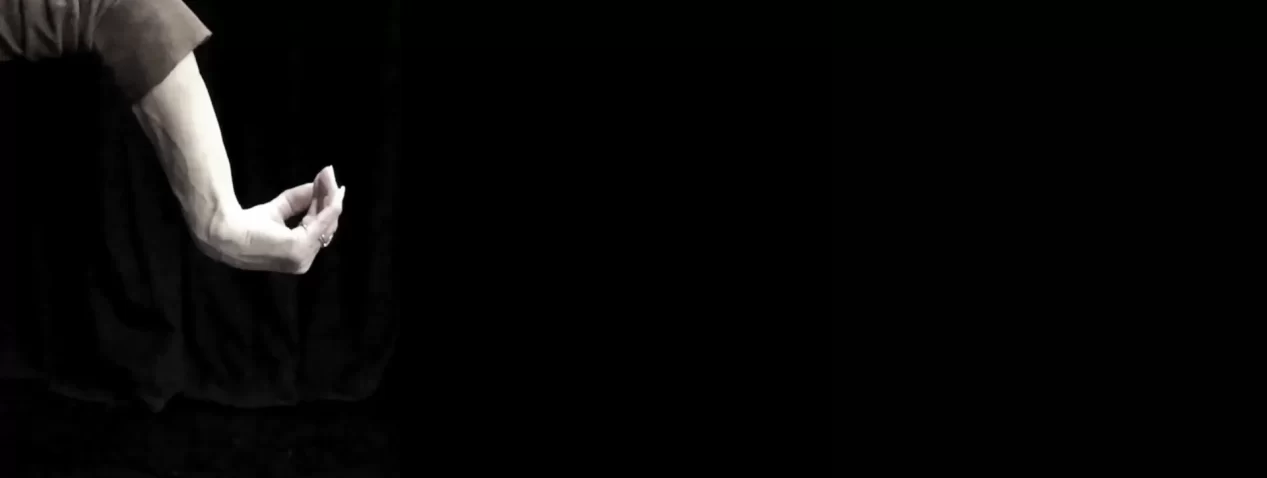 An image of an arm and hand agains a black background. The wrist, thumb and fingers are folding in towards the forearm.