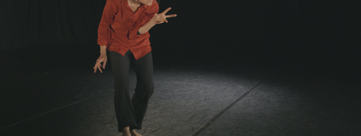 Person dancing with an intense attention, fingers reaching in odd directions, body hunched as if ready to pounce.