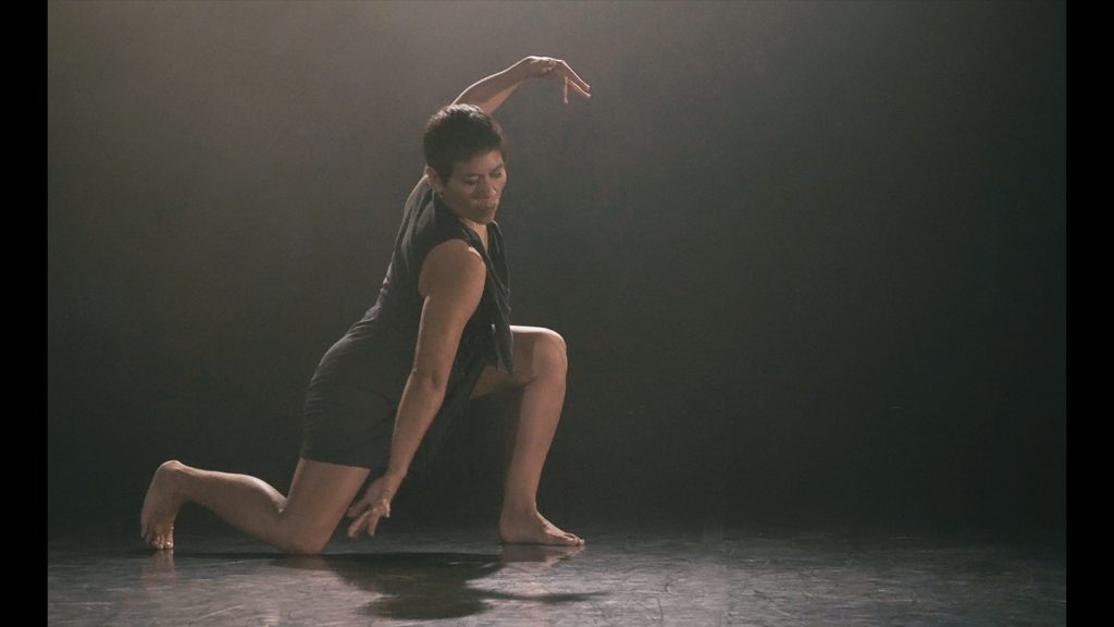 A person dancing, in deep powerful lunge.