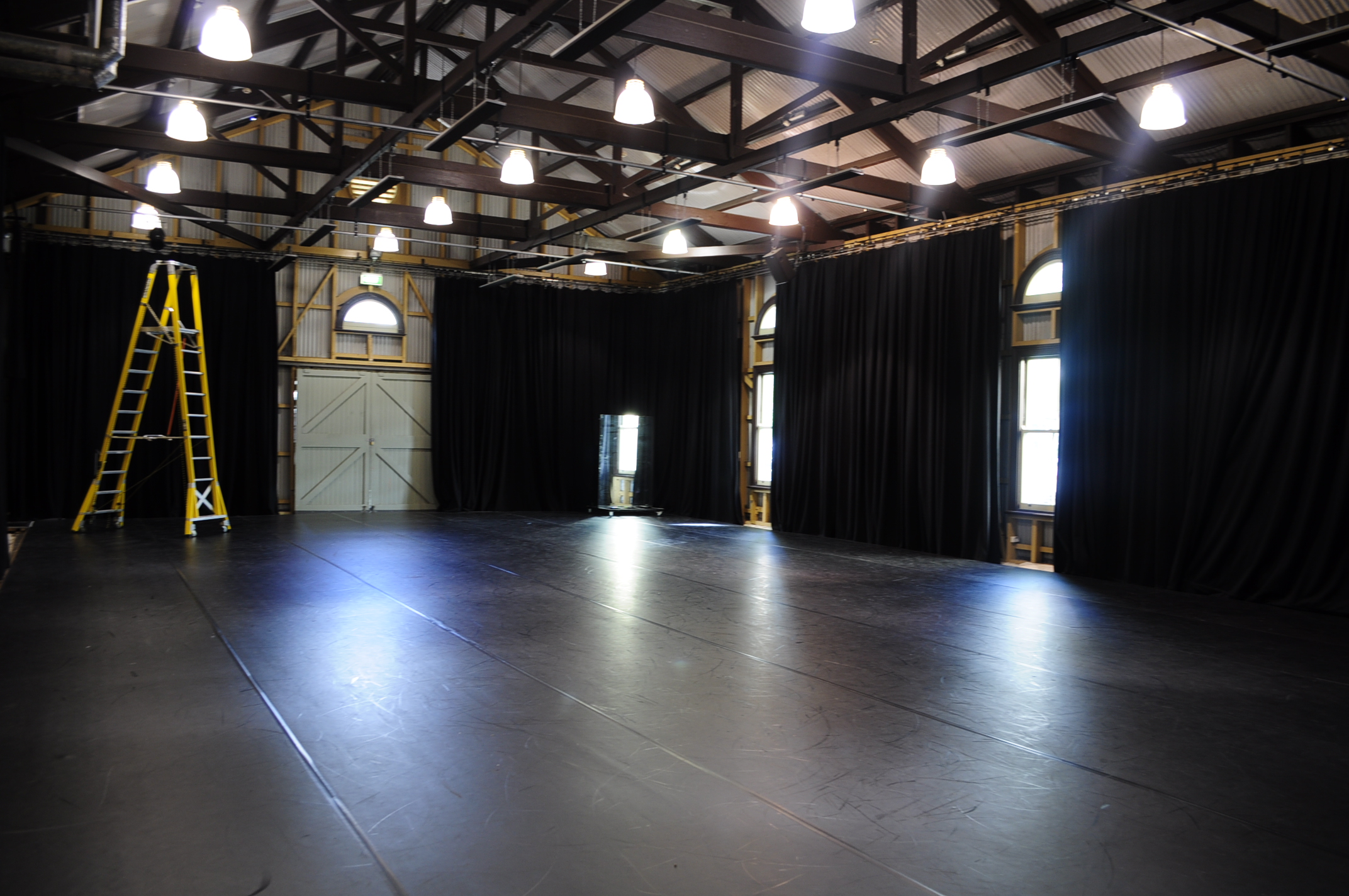 Image of a large empty room with black dance floor and high ceilings.